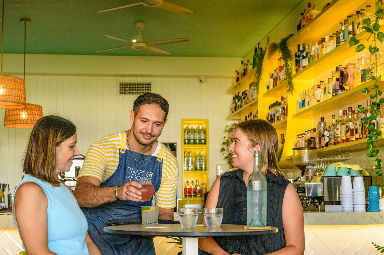 A Snapper Rocks team member sharing a tasting with guests at the bright yellow bar