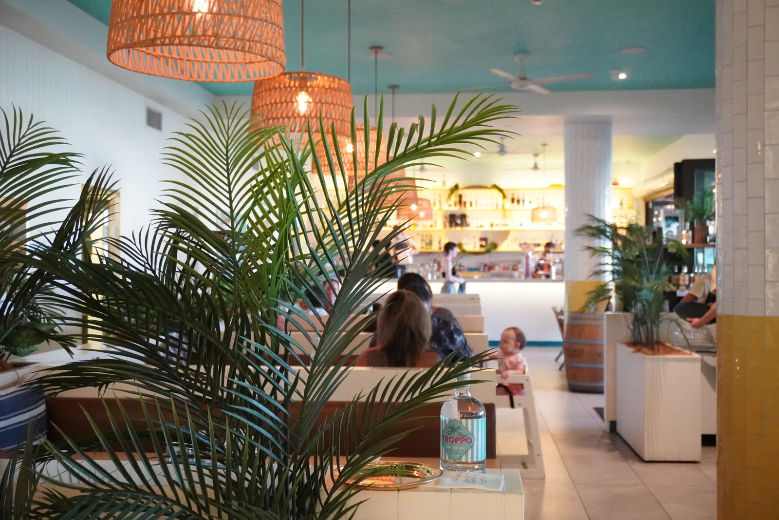 The relaxed Snapper Rocks dining room, with palms, woven lights and booth seating