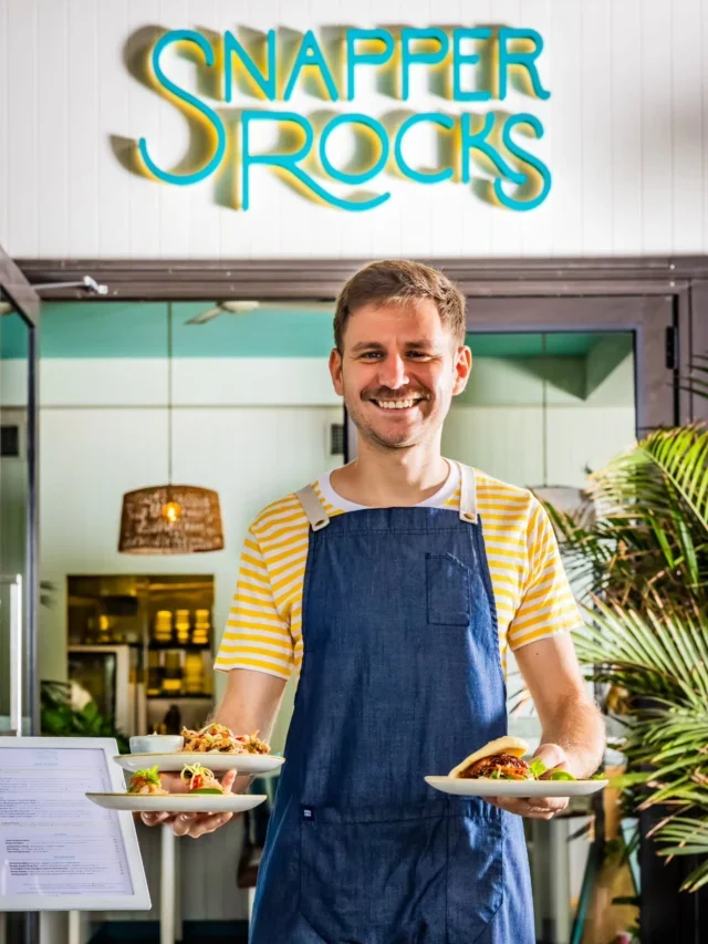 A smiling Snapper Rocks team member welcoming guests with drinks